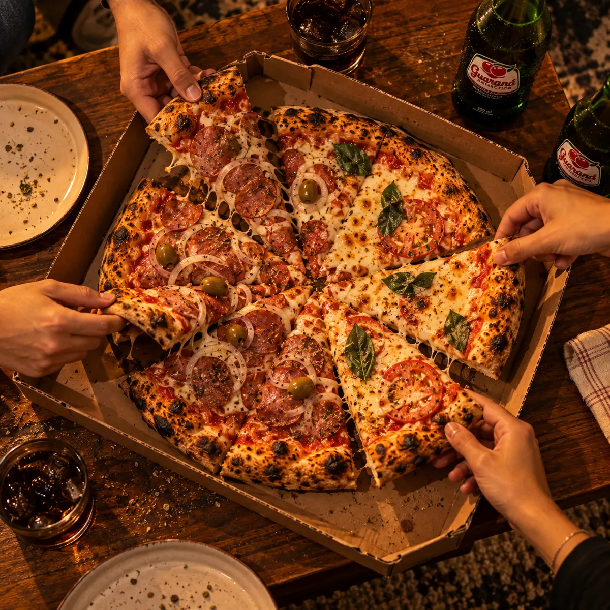 Pizza na caixa aberta, mãos pegando fatias